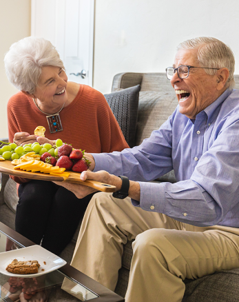 two concordia residents laughing while sharing a fruit platter