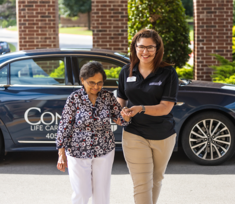 a concordia employee assisting a resident walk from the car